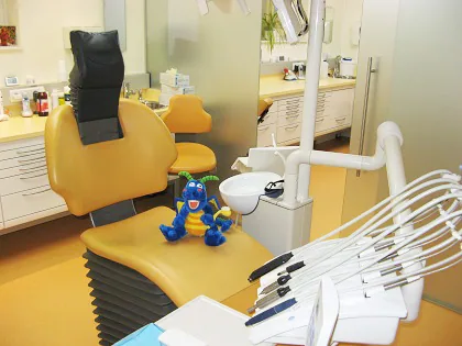 Behandlungszimmer mit gelbem Stuhl und einem Stoffdrachen